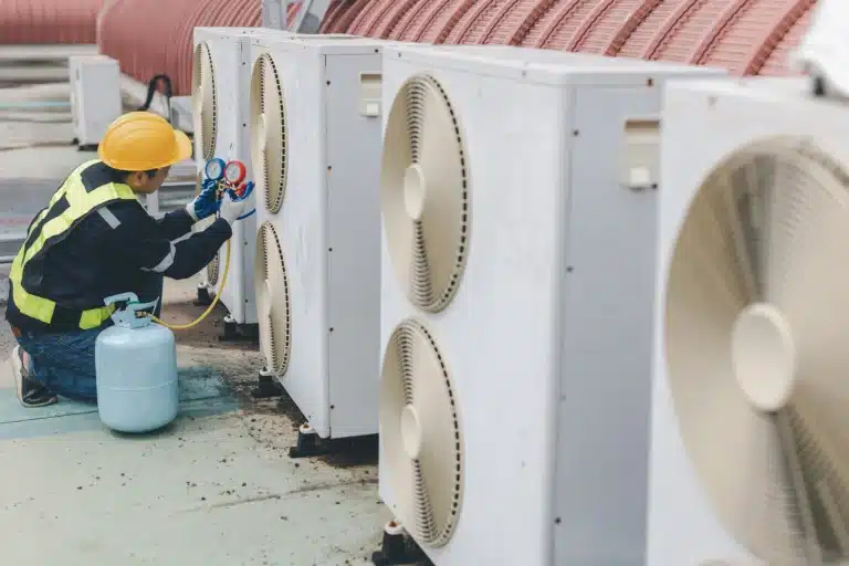 Technician in a hard hat servicing commercial rooftop AC units