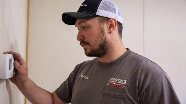 Technician checking a thermostat inside a home