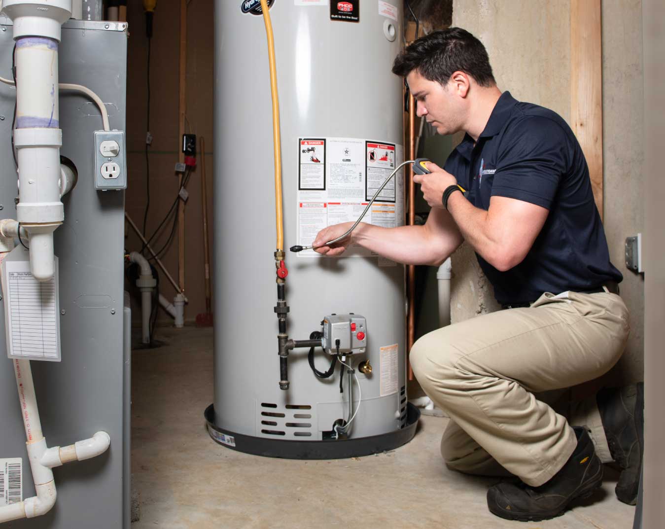 Technician servicing a tank water heater in a utility closet
